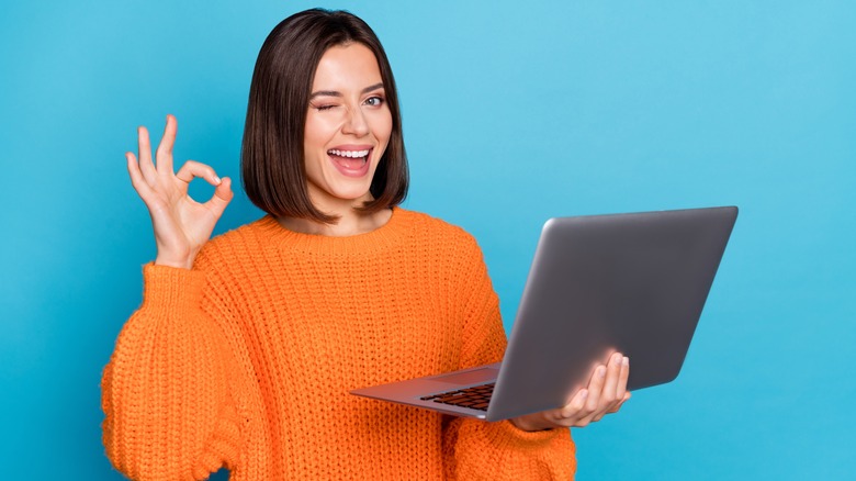 woman wearing orange sweater holding laptop