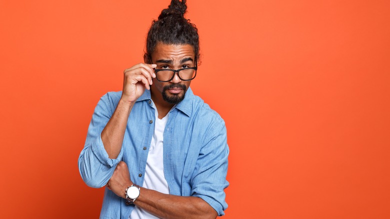 man standing against orange background with glasses on