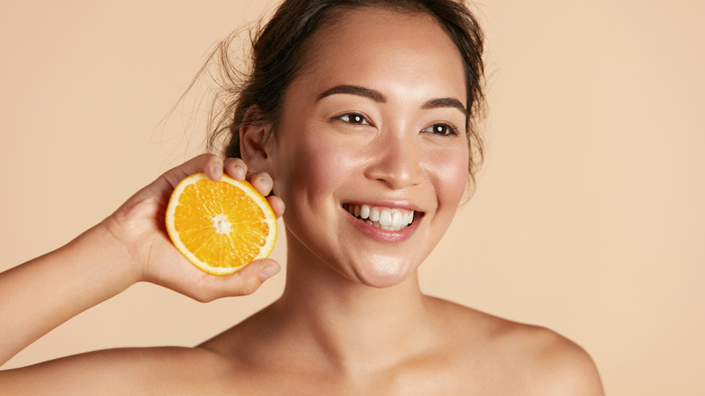 woman smiling holding half an orange