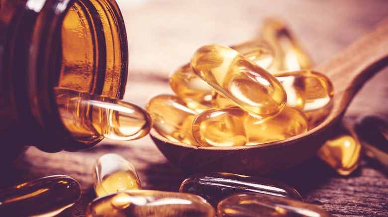 Vitamin D and omega supplements in jar and spoon