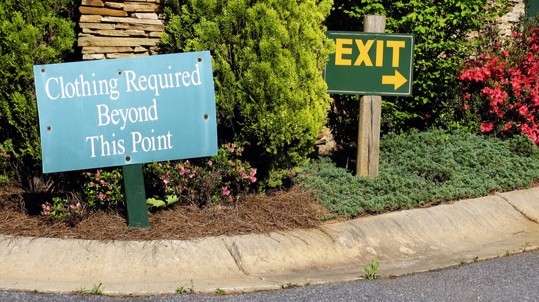 Sign reading "Clothing Required Beyond This Point" next to an EXIT sign