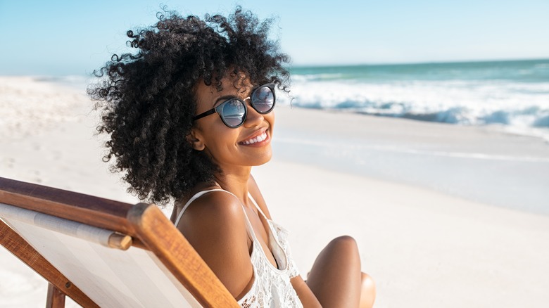 smiling woman on beach chair wearing sunglasses 