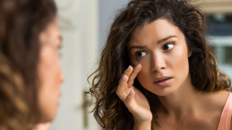 concerned brunette woman looking at mirror