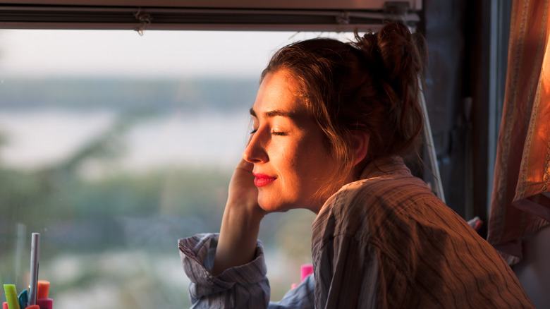 woman facing window morning sunlight