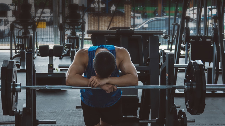 Man feeling tired and fatigued while in the gym