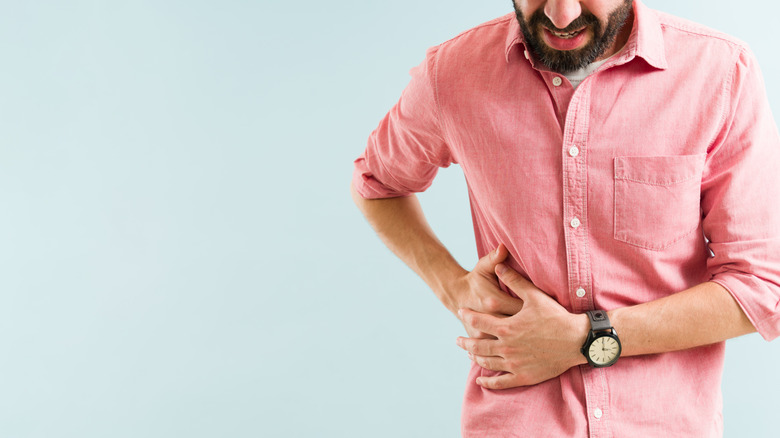 A man grimacing while holding his abdomen