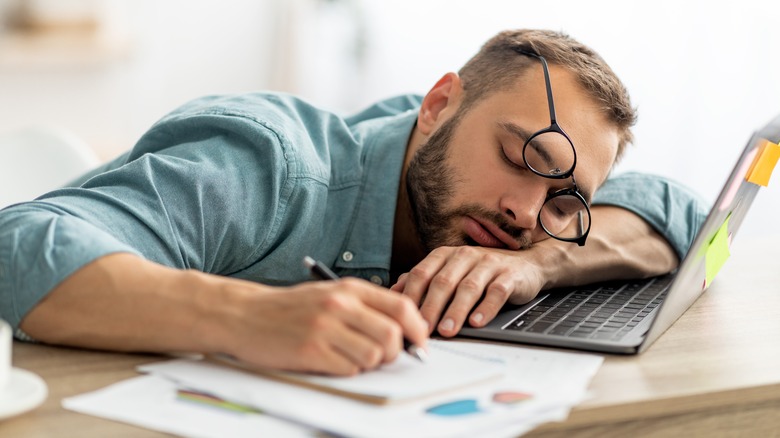 A man asleep at his laptop