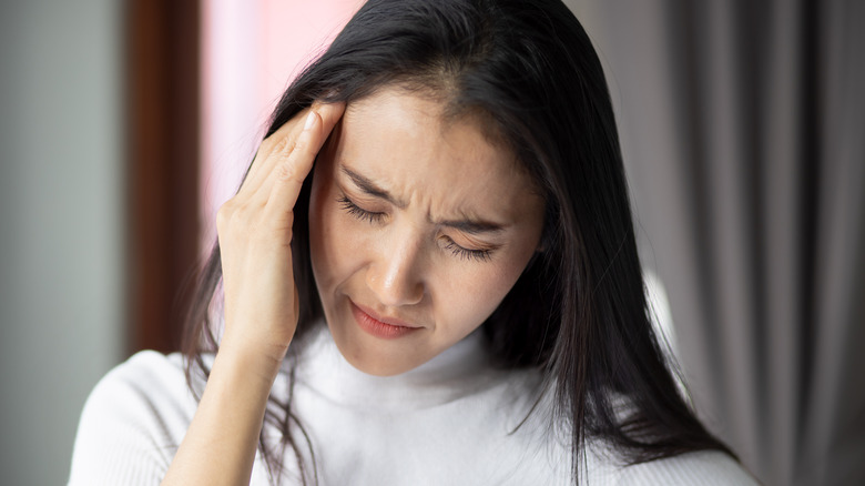 woman rubbing painful temple