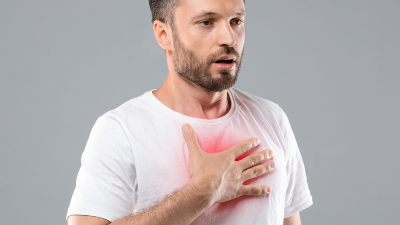 man touching chest having difficulty breathing