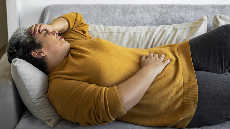 Woman lying on the couch with stomach pain