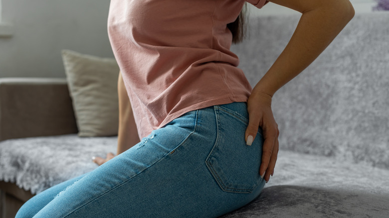 Woman holding buttocks due to hemorrhoid pain
