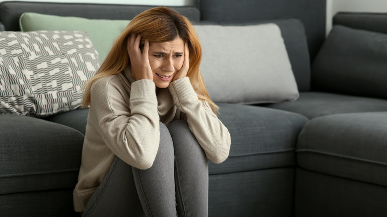 Woman seated against her couch having a panic attack