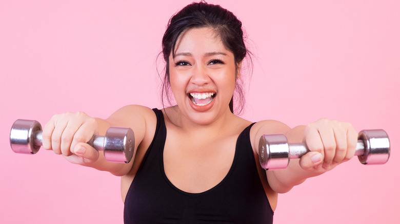 woman smiling and lifting free weights