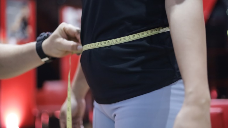 Measuring tape around person's abdomen