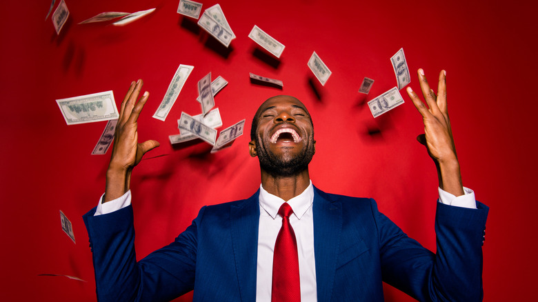 Smiling man surrounded by money