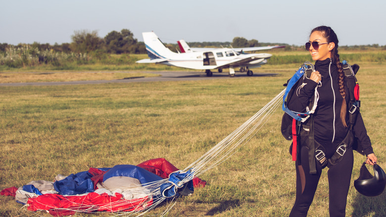 Woman skydiver landing with a parachute near a plane