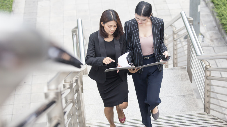 Business women talking and walking up stairs