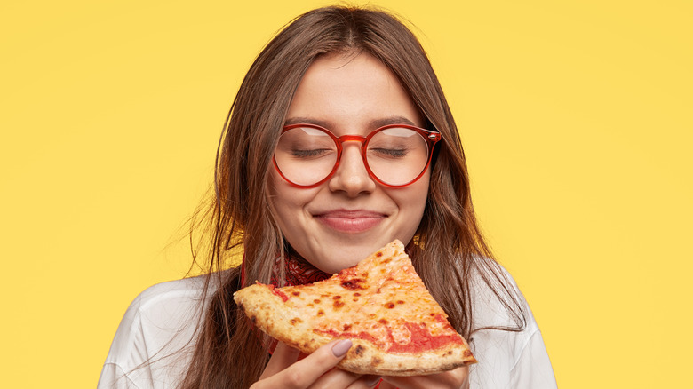 teen girl eating slice of pizza