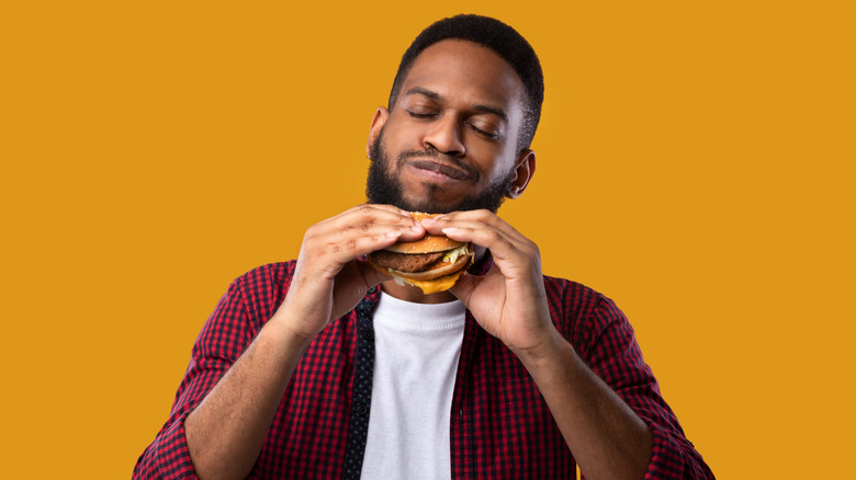 A man enjoys a hamburger