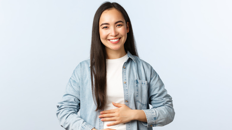 woman holding stomach and smiling