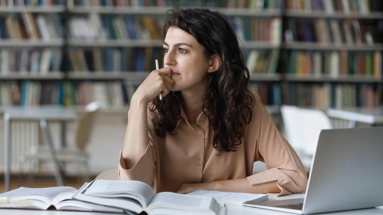 Woman working in library thinking 