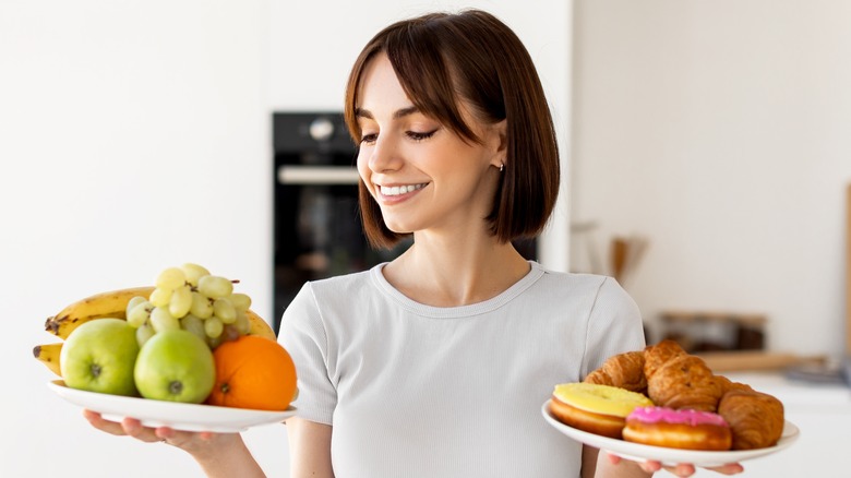 woman holding plate of fruit and donuts