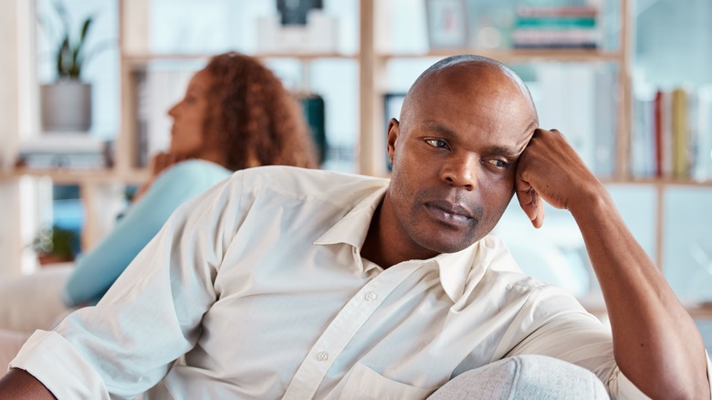 A bald man looking despondent as his partner faces away from him