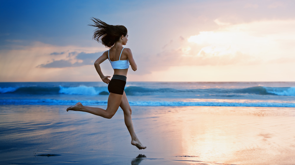 Woman running barefoot on beach