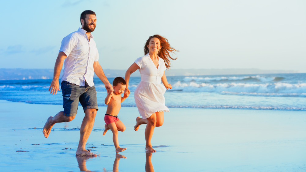 family running barefoot on sand