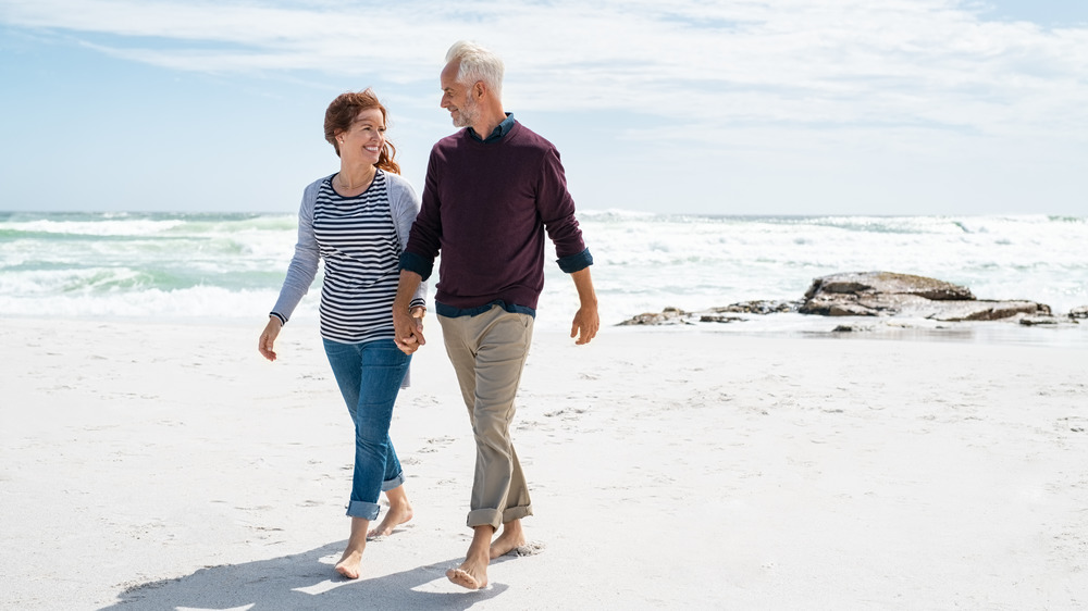 Couple walking barefoot, hand in hand, on the beach