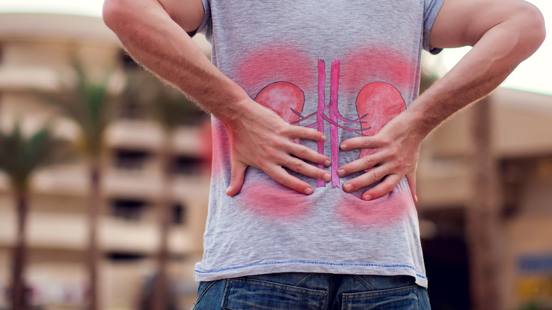 Man wearing a shirt with an image of kidneys and holding his lower back