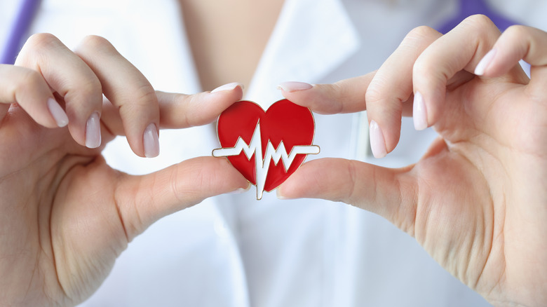 Close up of a doctor's hands holding a pin of a heart with an EKG line over it