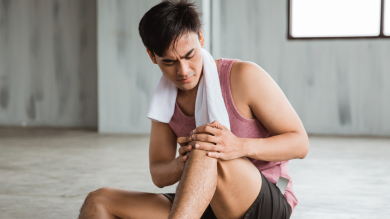 Man sitting on the ground holding his knee