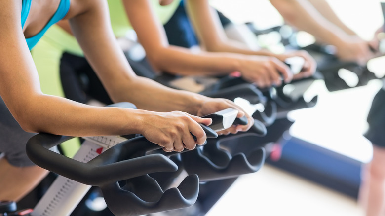 Close up of people's arms as they work out on stationary bikes