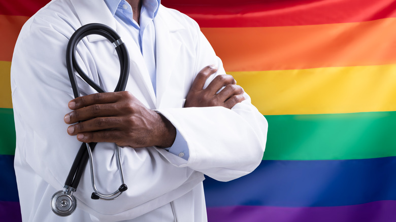 healthcare provider in front of rainbow flag