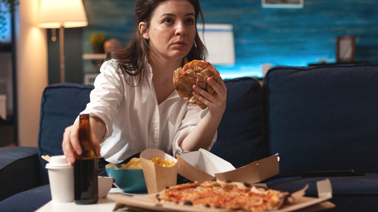 woman watches tv news while eating hamburger