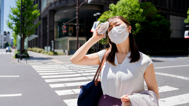 Woman touching forehead with face mask