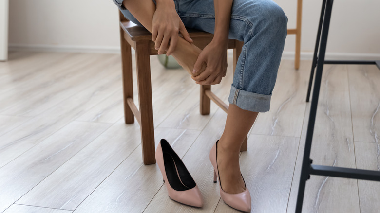 Woman wearing high heels, holding foot in pain
