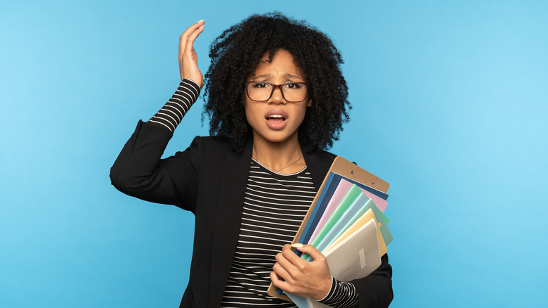 confused woman with glasses holding colorful folders