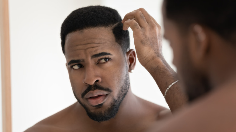 concerned man examining his hair in mirror