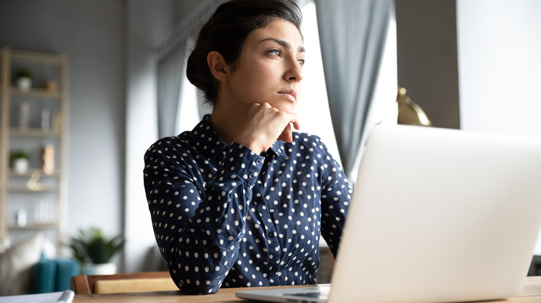 woman staring out window on her laptop