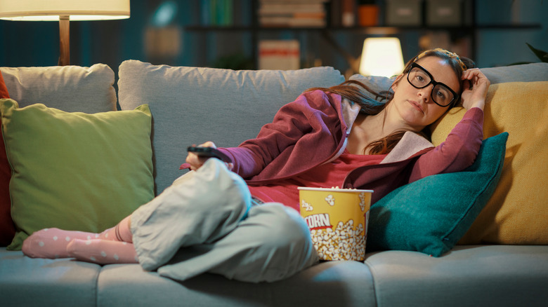 woman on couch with popcorn and tv remote