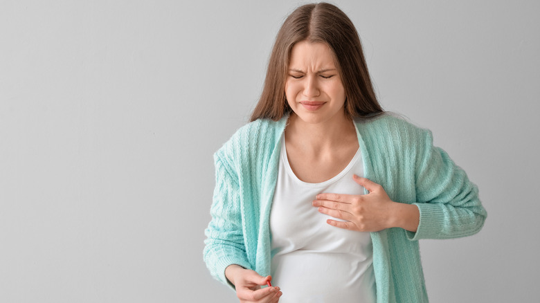 A woman with her hand on her breast in pain