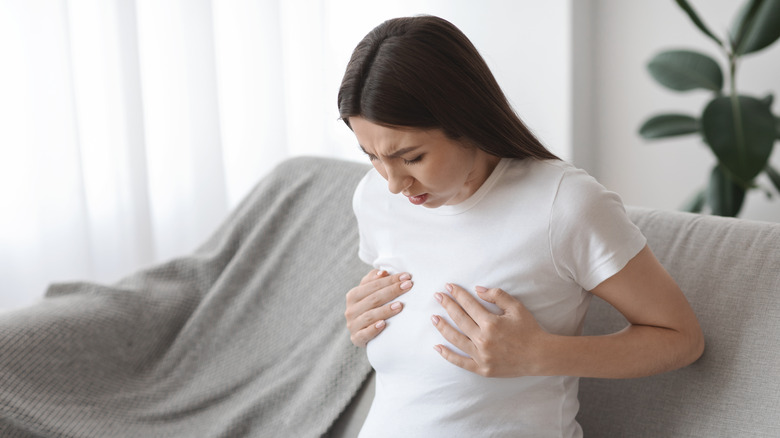 woman holding her breasts in pain