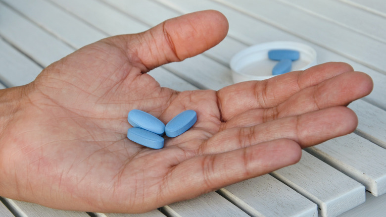 man's hand holding blue pills