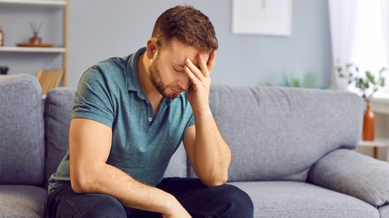 man sitting on couch experiencing a headache