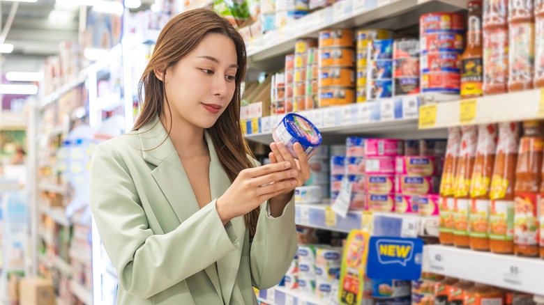 A woman looking at the label of a can of tuna