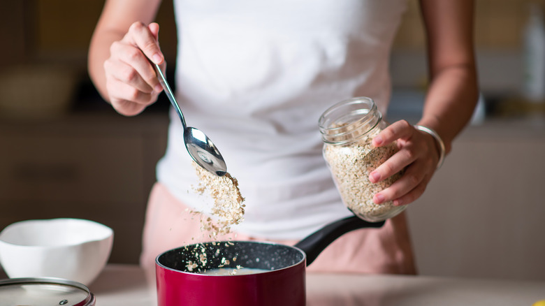 Woman making oatmeal in pan in kitchen