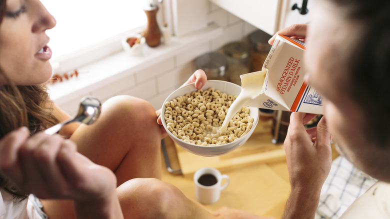 Man pours milk into woman's cereal bowl