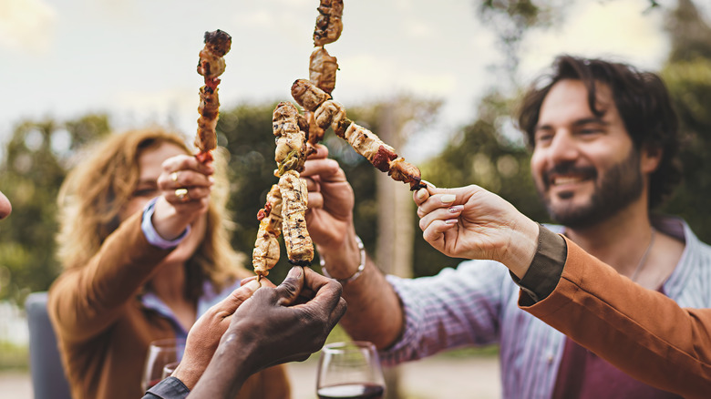 young friends eating meat skewers